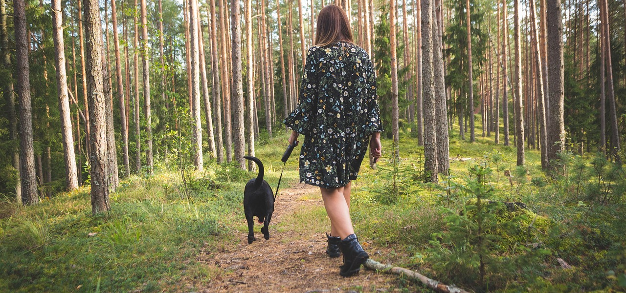 woman with black dog walking in woodland